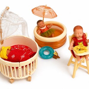 May include: A set of baby doll toys featuring a crib with a canopy, a baby in a paddling pool with a parasol, and a baby in a high chair. The dolls wear red and yellow outfits. A blue inflatable ring is also included.