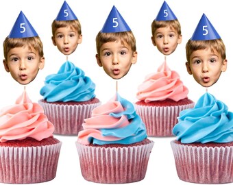 May include: Six cupcakes with red velvet cake bases and white paper liners. Each cupcake is topped with pink or blue frosting. A blue party hat with the number 5 and a child's face are attached to each cupcake.