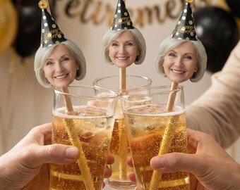 May include: A festive retirement celebration featuring three glasses of a bubbly beverage, each with a straw topped with a smiling face wearing a party hat. The background includes gold and black balloons and a banner that reads "Happy Retirement."