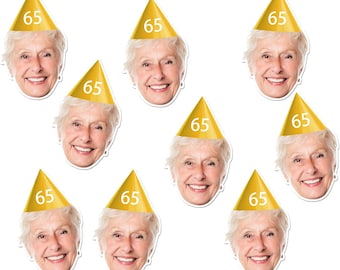 May include: A collection of die-cut face cutouts of a smiling older woman wearing a gold party hat with the number 65 printed on it. The cutouts are arranged against a white background.