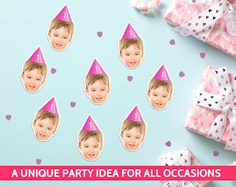 May include: Nine stickers of a baby's face wearing a pink party hat with the number 1. The stickers are scattered on a light blue surface with pink heart confetti and wrapped gifts. The text at the bottom reads "A UNIQUE PARTY IDEA FOR ALL OCCASIONS."
