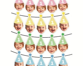 May include: A decorative party banner featuring twenty individual cutouts arranged in four rows. Each cutout displays a smiling baby wearing a colorful gingham party hat with the number one printed on the front in white, suspended on black strings.