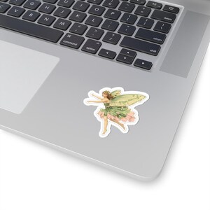 Könnte beinhalten: Ein Aufkleber mit einer Vintage-Illustration einer Fee mit grünen Flügeln und einem grün-rosa Kleid. Die Fee befindet sich in einer Tanzpose mit ausgestreckten Armen. Der Aufkleber befindet sich auf einem Laptop.