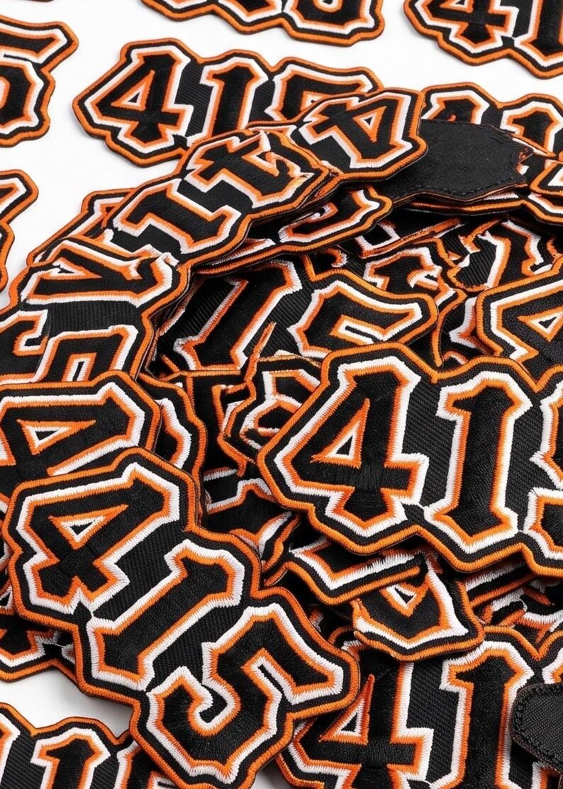 415 embroidered patch featuring bold varsity-style numbers with black, white, and orange outline design. High-quality stitched number patch inspired by streetwear and urban fashion, perfect for jackets, hoodies, hats, and backpacks.