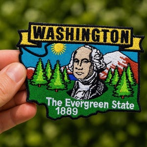 Könnte beinhalten: Gestickter Aufnäher mit einem farbenfrohen Design des Bundesstaates Washington. Der Aufnäher enthält den Text "WASHINGTON", ein Porträt von George Washington, immergrüne Bäume, einen Berg und den Text "The Evergreen State 1889".