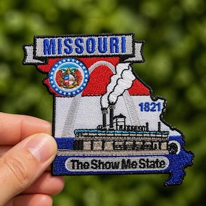 May include: Embroidered patch in the shape of Missouri, featuring the state's name, seal, and the text "The Show Me State." The patch includes a steamboat illustration and the year 1821, with a red, white, and blue color scheme.
