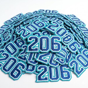 206 embroidered patch featuring bold varsity-style numbers with blue and teal outline design. High-quality stitched number patch inspired by streetwear and urban fashion