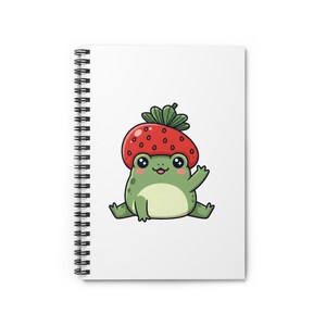 Puede incluir: Un cuaderno de espiral blanco con una portada que presenta una rana de dibujos animados con un sombrero de fresa. La rana es verde con una barriga verde claro, ojos negros y está saludando. El sombrero de fresa es rojo con hojas verdes.