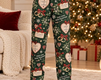 Pode incluir: Calças de pijama verde-escuras com um padrão repetitivo de corações brancos com o texto Emily & James, laços vermelhos, alianças de casamento douradas, visco, flocos de neve e etiquetas retangulares com a data 14 de dezembro de 2016.