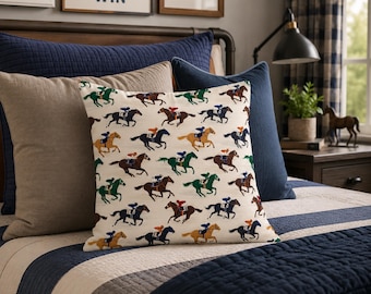 May include: A square scatter cushion featuring a repeating pattern of racehorses with jockeys in various colours on an off-white background. The cushion is positioned on a bed with navy blue and beige quilted bedding and solid-coloured accent cushions.