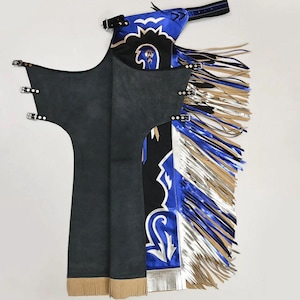 Op de afbeelding: Zwarte suède chaps met decoratieve blauwe, zilveren en zwarte accenten. De chaps hebben een gedetailleerd ontwerp met franjes en gespsluitingen. Het ontwerp omvat een blauwe top met zilveren en zwarte patronen en franjes.