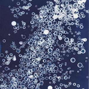 Può includere: Una stampa cianotipica che presenta una disposizione densa e sparsa di forme geometriche bianche su uno sfondo blu navy profondo. La composizione include numerosi cerchi, stelle, quadrati e forme a goccia, creando un motivo strutturato sulla superficie rettangolare.
