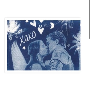 Può includere: Una stampa cianotipica blu e bianca che raffigura una coppia che si bacia, con una figura che indossa ali d'angelo. Il design include il testo XOXO, stelle, cuori, una luna crescente e palme, in uno stile monocromatico ad alto contrasto.