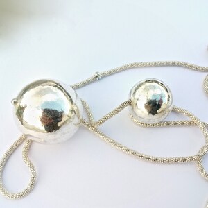 May include: A silver necklace with two hammered silver spheres. The necklace is made of a fine chain.