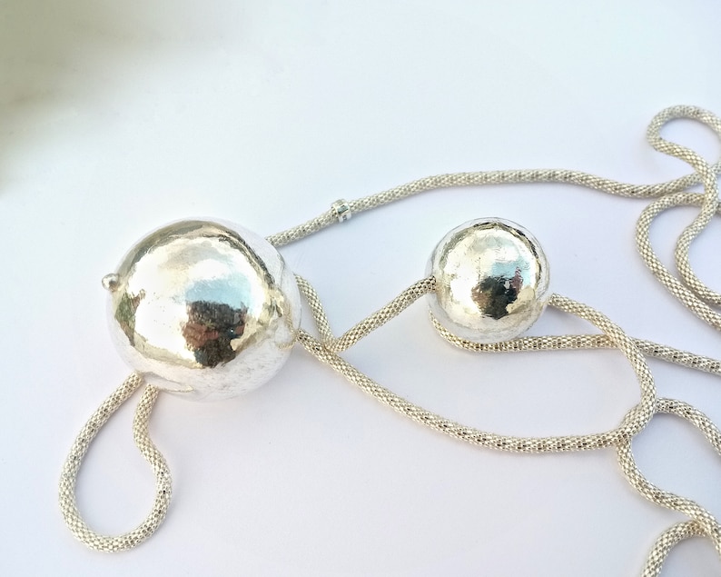 May include: A silver necklace with two hammered silver spheres. The necklace is made of a fine chain.