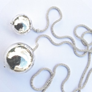 May include: A silver chain necklace with two large, round, hammered silver pendants.