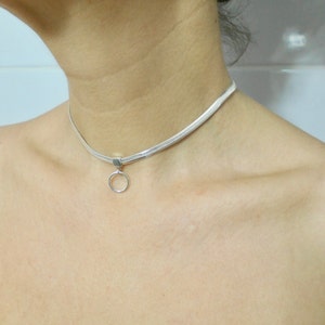 K&ouml;nnte beinhalten: Eine silberne Choker-Kette mit einem kleinen, runden Anh&auml;nger.