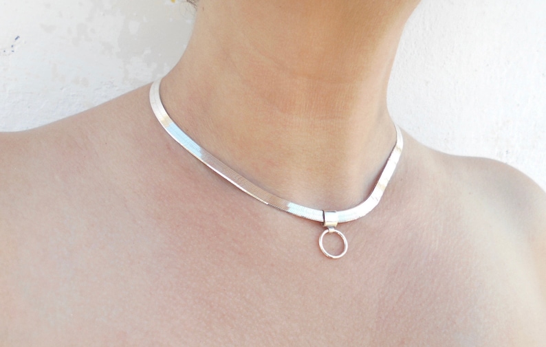 May include: A silver choker necklace with a simple circle pendant.