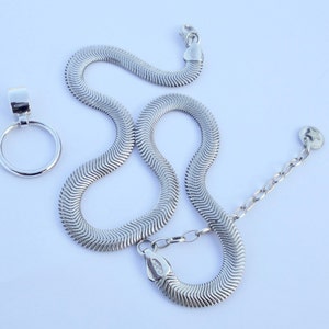 May include: A silver-colored necklace with a herringbone chain design, and a separate pendant with a circular loop. The necklace has a lobster clasp and an adjustable chain. The jewelry is displayed on a white background.
