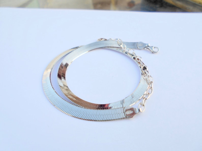 Pu&ograve; includere: Una collana a catena di serpente d'argento con una finitura lucida. La catena &egrave; realizzata con maglie intrecciate che creano un aspetto liscio e fluido.