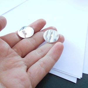 May include: Two silver round metal discs, one with a simple design and the other with a textured surface.