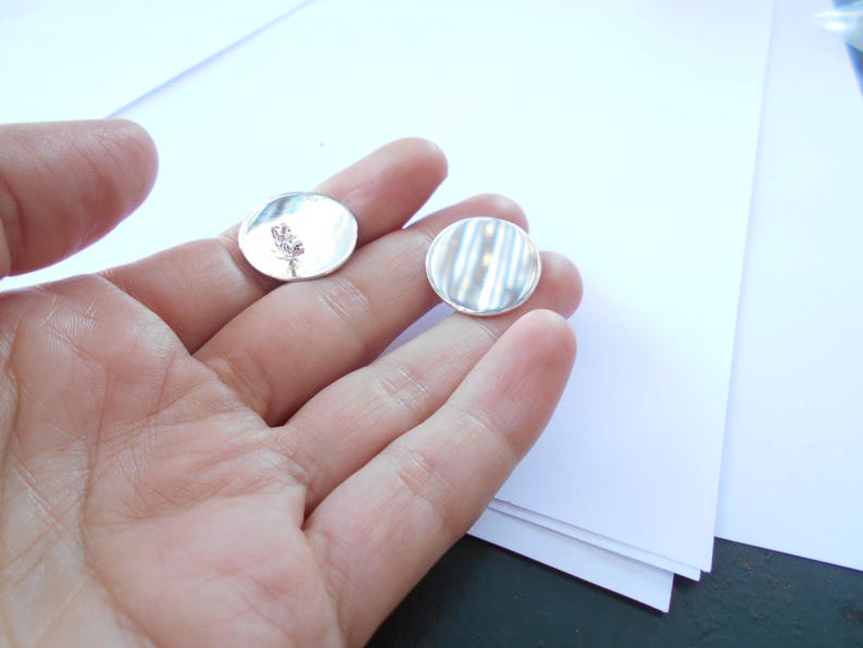 May include: Two silver round metal discs, one with a simple design and the other with a textured surface.