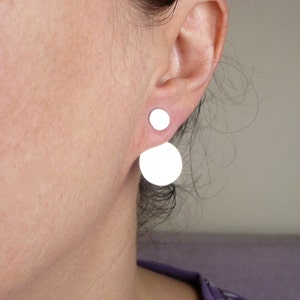 May include: A pair of silver earrings with a small round disc on top and a larger round disc hanging below.
