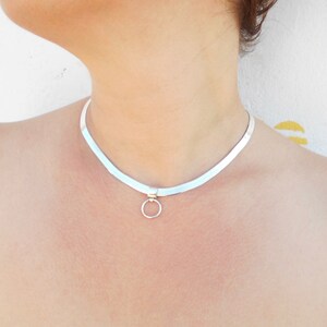 May include: A silver choker necklace with a small circle pendant.