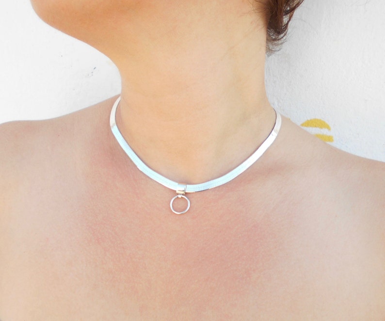 May include: A silver choker necklace with a small circle pendant.