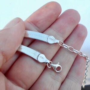 May include: A silver snake chain necklace with a lobster clasp. The chain is made of small, interlocking links that create a smooth, flowing look.