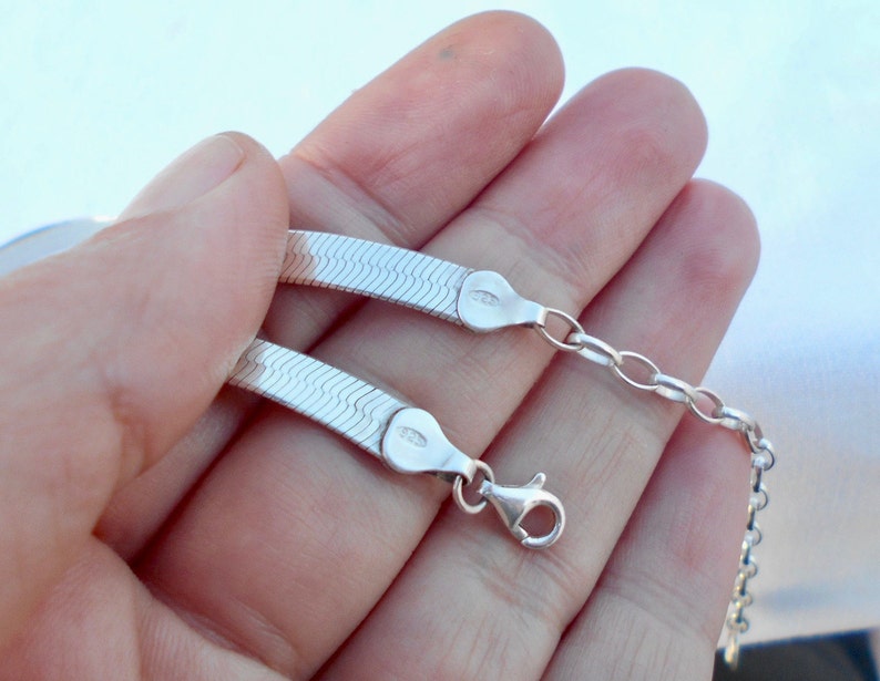 May include: A silver snake chain necklace with a lobster clasp. The chain is made of small, interlocking links that create a smooth, flowing look.