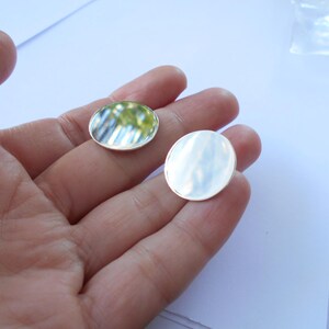 May include: Two round, silver-colored metal discs. The discs are smooth and reflective. The discs are about 1 inch in diameter.