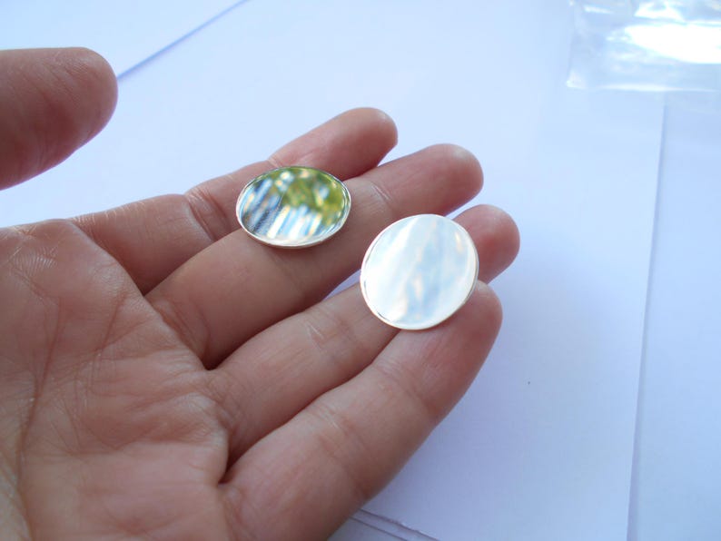 May include: Two round, silver-colored metal discs. The discs are smooth and reflective. The discs are about 1 inch in diameter.