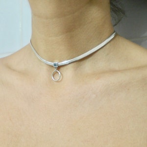 K&ouml;nnte beinhalten: Eine silberne Choker-Kette mit einem kleinen, runden Anh&auml;nger.