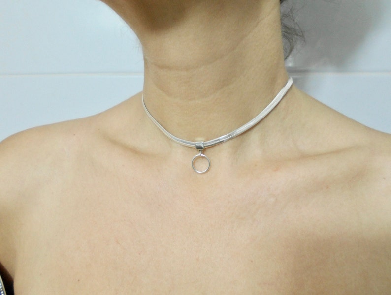 K&ouml;nnte beinhalten: Eine silberne Choker-Kette mit einem kleinen runden Anh&auml;nger.