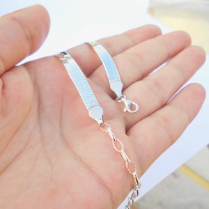 Pu&ograve; includere: Due catene d'argento, una con un motivo a catena di serpente e l'altra con un motivo a catena a maglie pi&ugrave; tradizionale.