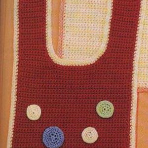 May include: A handmade, crocheted bib in a deep red color with a cream-colored border. The bib features several crocheted circles in various colors, including blue, green, and cream. A button is visible at the top. The bib is designed for a baby or toddler.