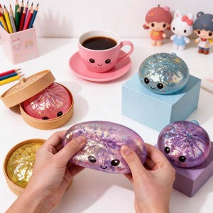 Puede incluir: Una variedad de artículos de temática kawaii. Incluye una taza rosa con una cara sonriente, juguetes decorativos con forma de dumpling y pequeñas figuras. Los juguetes son iridiscentes y brillantes. Lápices y crayones en el fondo.