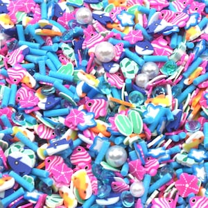 May include: A collection of colorful polymer clay sprinkles featuring miniature shapes of fish, starfish, and flip-flops mixed with blue rod-shaped pieces, translucent blue gems, and round white faux pearls in a vibrant, multi-colored assortment.