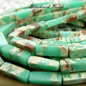 May include: Close-up of a strand of rectangular beads. The beads are a light green color with patches of cream and reddish-brown. The text "Blackrock Beads" is in the upper right corner. The beads are likely for jewelry making.