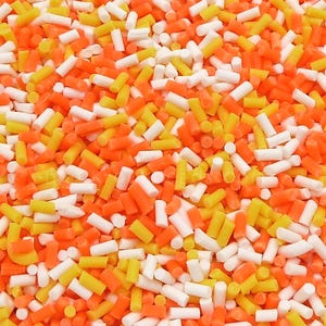 May include: A dense collection of small, cylindrical sugar sprinkles in a vibrant mix of bright orange, sunny yellow, and crisp white. Each individual piece is uniform in shape, creating a textured, colorful surface of edible decorations.