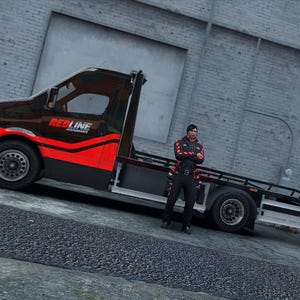 Può includere: Un carro attrezzi nero e rosso con la scritta "REDLINE PERFORMANCE" sul lato. Il camion è parcheggiato su una superficie pavimentata accanto a un edificio in mattoni. Una persona in uniforme nera e rossa è in piedi accanto al camion.