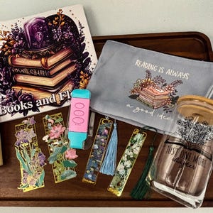 May include: A collection of book-themed items on a wooden tray. Includes a book with the title "Books and Flowers", a pencil case with the text "Reading is Always a Good Idea", decorative bookmarks, a glass jar, and a pencil set.