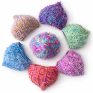 May include: A selection of hand-knitted hats and a headband in a circular arrangement. The hats display a range of colours, such as blue, purple, pink, green, and orange. The textures appear soft and fuzzy, giving a cosy, handmade appearance.