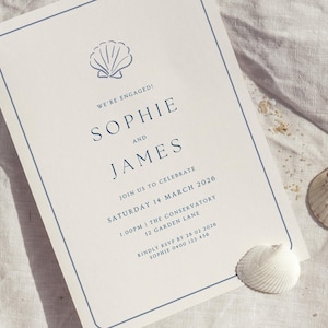 May include: An invitation with a seashell graphic and text that reads "We're Engaged! Sophie and James." The invitation is bordered in blue and includes event details for March 14, 2026. Two seashells are placed near the invitation on a white surface.