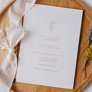 May include: A white rectangular baptism invitation card with pink text and a small floral illustration. The text reads: We invite you to celebrate THE BAPTISM OF OLIVIA, SUNDAY, 18 OCTOBER 2026 | 11:00AM, ST MICHAEL'S CHAPEL, ROSEWOOD GARDENS, LUNCH TO FOLLOW, RSVP BY 20 SEPTEMBER 2026.