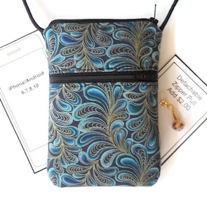 May include: A small blue and gold patterned crossbody bag with a zipper closure. The bag is designed to fit an iPhone or Android phone up to size 10.  The text "iPhone/Android 6,7,8,10" is visible on the left side of the image.  The text "Detachable Zipper Pull Add $2.00" is visible on the right side of the image.
