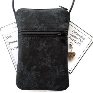 May include: Black crossbody bag with a floral pattern and two zippered compartments. The bag has a detachable zipper pull, which is an optional add-on for $2.00.