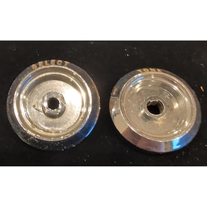 Op de afbeelding: Twee vintage chromen bedieningsknoppen. Eén knop is gemarkeerd met "SELECT" en de andere met "TONE" in gouden letters. De knoppen hebben een cirkelvormig ontwerp met een centraal gat voor montage. Waarschijnlijk voor een vintage elektronisch apparaat.