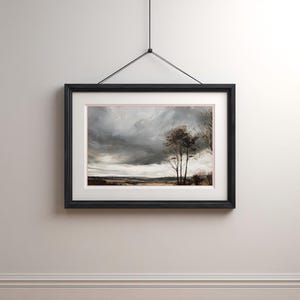 May include: A framed landscape painting featuring a dramatic sky with dark, swirling clouds. The artwork depicts a field with trees in the distance, framed in a black wooden frame with a white mat. The painting is hanging on a neutral-colored wall.